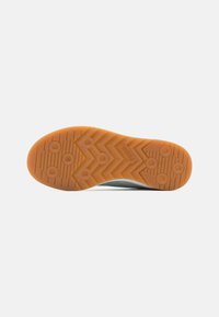 Sole of a sneaker with a zigzag traction pattern. Orange rubber material with circular and vertical ridges. Smooth edges, lightweight design.