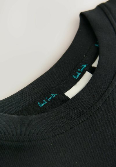 Must värviga meeskonnakaelusega T-särk, millel on sile puuvillane tekstuur. Silt "Paul Smith" türkiissinise värviga, õmmeldud detailid kaeluse ümber.