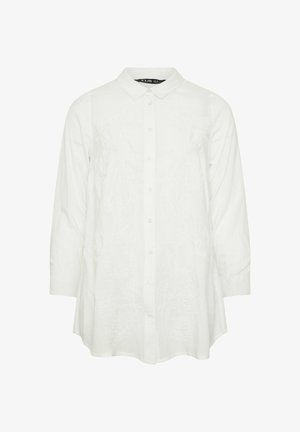 Camisa blanca de manga larga con botones, cuello y bordado floral sutil en la parte delantera, bajo ligeramente acampanado y puños con botones.