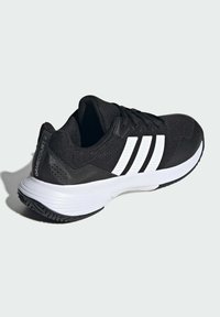 Czarny but sportowy z teksturowaną cholewką, trzema białymi paskami, białą, amortyzowaną podeszwą środkową oraz gumową podeszwą z geometrycznym wzorem bieżnika.