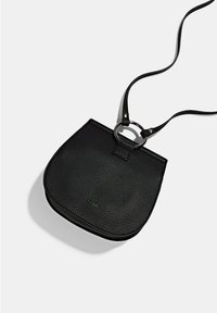 Bolso bandolera de cuero negro con textura de grano, forma redondeada y un acento de anillo circular. Presenta una correa delgada y ajustable.