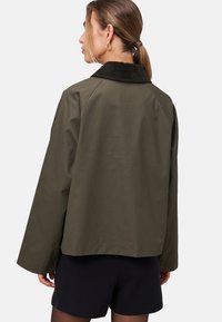Oliven grøn jakke med en kordfløjs krave, afslappet pasform, sænkede skuldrer og lange ærmer. Glat stof med en ren finish.