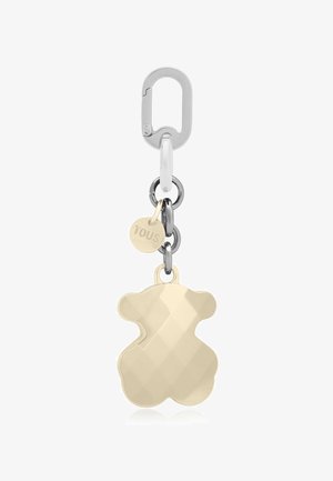 Portachiavi d'argento con un ciondolo a forma di orsetto d'oro e un piccolo medaglione rotondo inciso con la scritta "TOUS", collegati da anelli metallici.