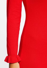 Rode gebreide mouw van een jurk met een aansluitend ontwerp en een uitlopende, gerimpelde manchetdetail. Zachte textuur met een gladde afwerking.