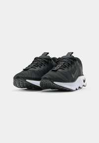 Black athletic shoes with a textured mesh upper, white midsole, and black tread pattern, featuring a prominent Nike logo on the side.