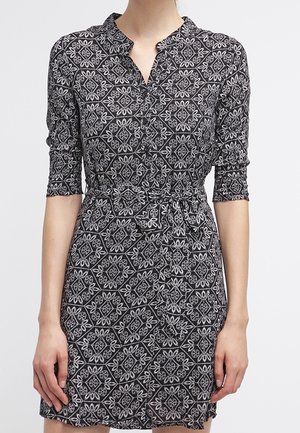 Czarna sukienka za kolano z białymi geometrycznymi kwiatowymi wzorami, rękawami do połowy przedramienia, dekoltem w serek i wiązanym paskiem w talii.
