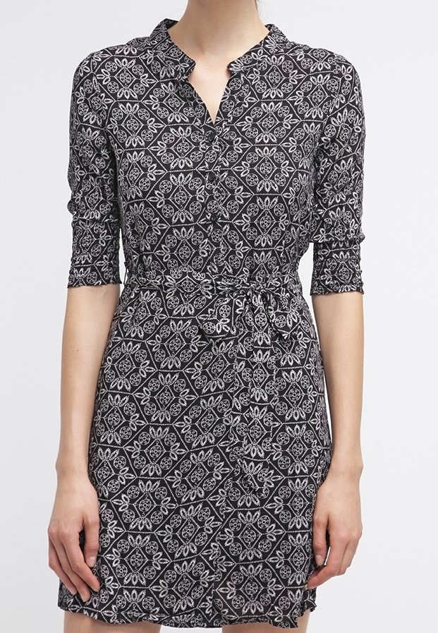 Robe noire longueur genou avec motifs floraux géométriques blancs, manches trois-quarts, décolleté en V et ceinture nouée à la taille.