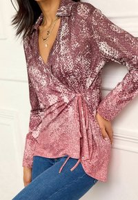 Blusa avvolgente a maniche lunghe in un motivo a gradiente di malva e rosa con un dettaglio di legatura laterale. Tessuto morbido con una texture liscia.