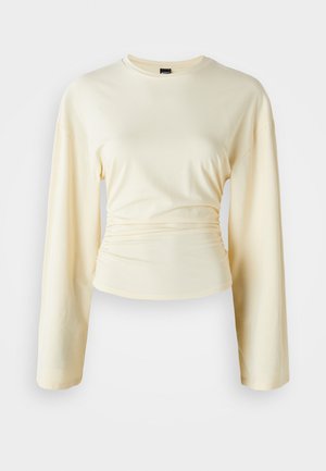 Light yellow long-sleeve shirt with a round neckline and gathered detailing at the waist. Made from soft, smooth fabric.