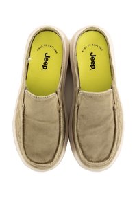 Zapatos beige tipo slip-on con una parte superior de lona, textura parecida al ante y suela de goma blanca. Presenta una plantilla de un amarillo brillante con la marca "Jeep".