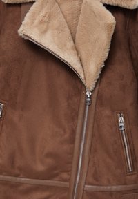 Brun suedetjakke med beige shearling krave, frontlynt og lynlåslommer på siden.