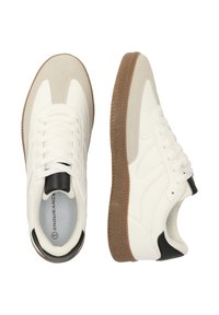 Vita sneakers med en slät läderdesign, mockadetaljer och en brun strukturerad gummisula; har svarta detaljer och snören.