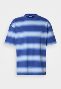 Camiseta de manga corta hecha de algodón con rayas horizontales en varios tonos de azul. Escote redondo, ajuste relajado y una etiqueta que muestra la marca.