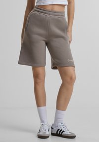 Grå sweatshorts med elastisk midje, sidelommer og subtilt logodesign. Glatt tekstur, knelengde.