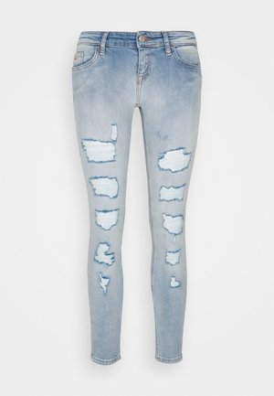 Jeans de denim azul claro con detalles desgastados, que cuentan con múltiples parches destruidos y un diseño ajustado. Estilo estándar de cinco bolsillos.