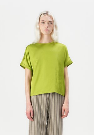 Green short-sleeve blouse with a loose fit, round neckline, and smooth texture. Paired with striped wide-leg trousers.