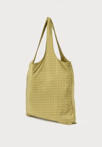 Zelena torba za nošenje z vzorcem in podolgovatimi, ravnimi trakovi. Izdelana iz blaga, s subtilnim geometrijskim vzorcem in prostornim glavnim predalom.