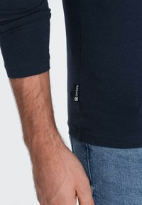 Laivaston pitkähihaisten paidan valmistuksessa on käytetty puuvillasekoitetta. Paidassa on pyöristetty helma, näkyvät saumat ja pieni logotagi sivussa.