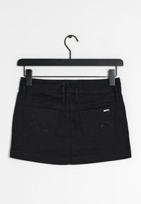 Jupe mini en denim noir avec une coupe droite, dotée de deux poches arrière et d'accents brodés. Elle est suspendue à un crochet en métal noir.