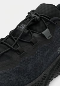 Μαύρο αθλητικό παπούτσι με υφασμάτινη επάνω επιφάνεια με υφή, ενσωματωμένο σύστημα κορδονιών και πατούσα με σχέδιο. Τα υλικά περιλαμβάνουν συνθετικό ύφασμα και καουτσούκ.