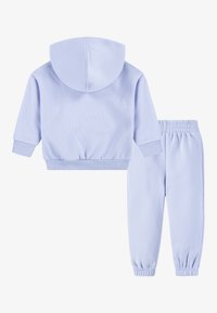 Hele sinise puuvillane kapuutsiga pusa, millel on nööriga kapuuts ja soonilised mansetid, koos sobivate kitsenevate dressipükstega, millel on elastne vöökoht.