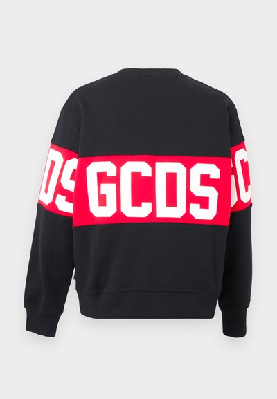 Čierna mikina s širokým červeným pásom a bielymi písmenami "GCSD" na chrbte. Ribované manžety a spodný lem. Bavlnený materiál, voľný strih.