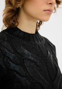 Schwarzer gestrickter Pullover mit einem strukturierten Zopfmuster. Verfügt über einen gerippten Rundhalsausschnitt und weiche, erhabene Fasern, die einen einzigartigen Look erzeugen.