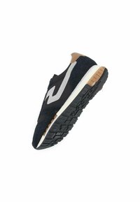 Sneaker noir avec une tige texturée, accents argentés et un talon marron. Comprend une semelle intermédiaire blanche et une semelle extérieure en caoutchouc à motifs.