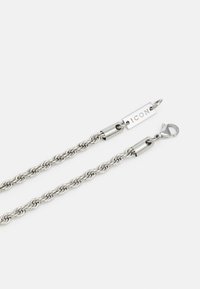 Collana di catena in argento con design intrecciato, dotata di chiusura e di un'etichetta incisa con la scritta "ICON." Superficie metallica liscia e finitura elegante.
