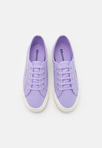 Sneaker in tela viola con punta rotonda, suola in gomma bianca a contrasto e lacci piatti. Logo "Superga" visibile sulla linguetta e sul lato.