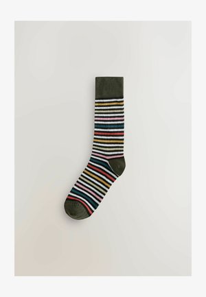 Chaussette rayée avec un bord côtelé vert foncé, en coton, présentant des rayures horizontales rouges, bleues, jaunes, roses et blanches.
