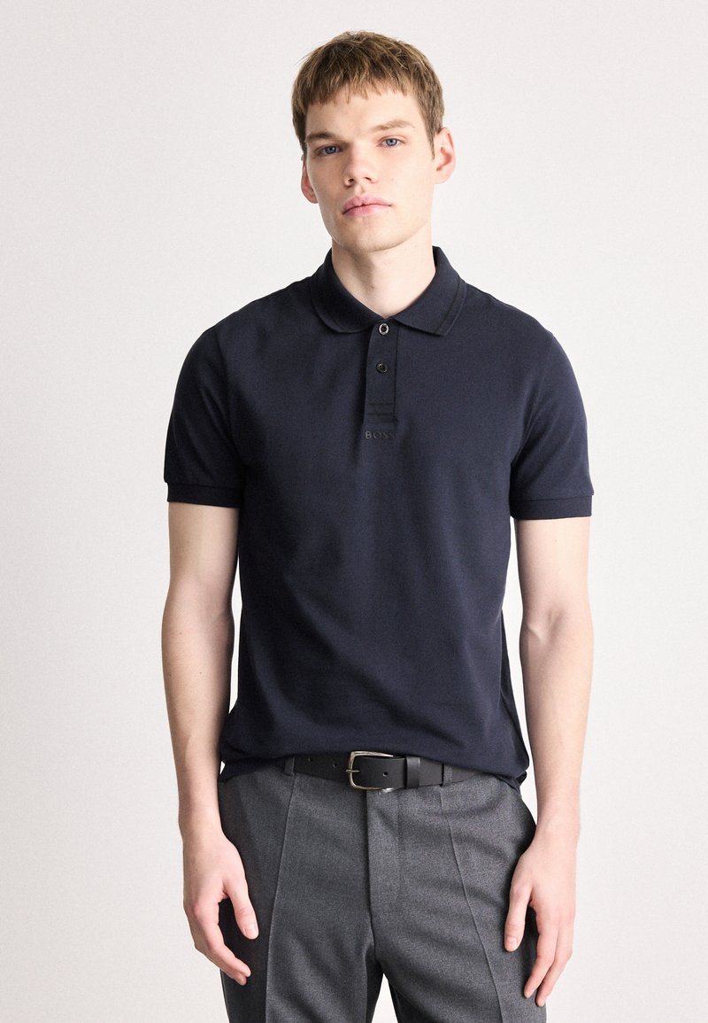 Ναυτικό μπλε πόλο μπλούζα από ελαφρύ ύφασμα με κοντά μανίκια, τρεις κουμπότρυπες και διακριτό λογότυπο της μάρκας στο στήθος.