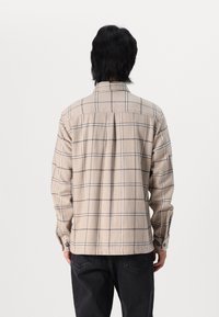 Beige geruite blouse met lange mouwen, knoopmanchetten en een zachte textuur. Kenmerkt zich door een rugpand en verticale plooien voor een goede pasvorm en comfort.