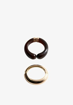 Two chunky cuff bracelets, one dark brown resin with a gold clasp, one smooth gold-tone metal with a hinge closure, on white background.