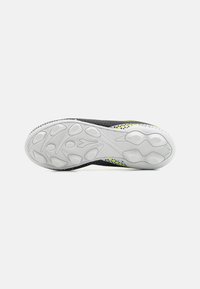 Scarpa sportiva nera con tomaia texturizzata, dotata di suola in gomma bianca e accenti colorati lungo il lato, progettata per la trazione e il comfort.