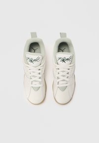 Białe sneakersy z górną częścią z gładkiej skóry, teksturowanymi akcentami z zamszu, zielonymi przeszyciami i podeszwa z gumy. Posiadają sznurowane zapięcie i pętelkę do zakładania.