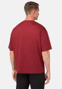 T-shirt rossa a maniche corte realizzata in cotone morbido. Caratterizzata da un classico collo a giro e una vestibilità rilassata, senza loghi o motivi visibili.
