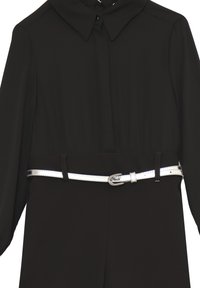 Tuta nera con colletto, maniche lunghe e vita cinchata. Presenta una cintura argentata metallica con una fibbia, texture del tessuto liscia.
