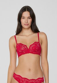 Červená krajková bralette s kosticemi, průsvitný design, vroubkované okraje a nastavitelné ramínka. Jsou k dispozici odpovídající krajkové kalhotky.