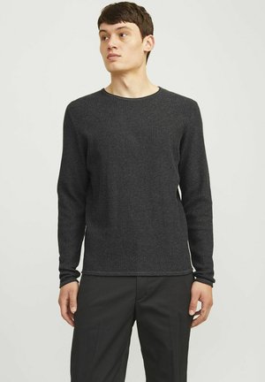 Zwarte sweater met lange mouwen in een gestructureerde brei, met een ronde hals en een aansluitende pasvorm, gecombineerd met zwarte broek voor een samenhangende uitstraling.