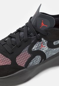 Baskets noires et grises avec motif en grille, lacets noirs et petits logos Jumpman rouges sur le côté et la languette.