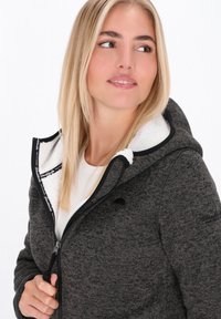 Sivá mikina s kapucňou na zips s bielou fleecovou podšívkou, čiernymi akcentmi a textúrovanou tkaninou. Má kapucňu a predné zapínanie na zips.