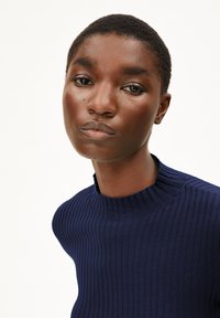 Dunkelblauer gerippter Strickpullover mit hohem Kragen und strukturiertem Kragen. Enganliegendes Design mit strukturiertem Stoff und dezenten Details.