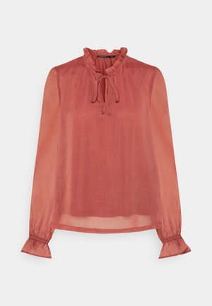 Hento ruosteenvärinen pitkähihainen pusero, jossa röyhelökaulus ja kalvosimet sekä solmimisnauha kauluksessa.