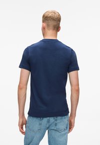 Marineblauwe t-shirt met korte mouwen en ronde hals, gemaakt van een zachte stof, gecombineerd met lichtblauwe jeans met achterzakken en een losse pasvorm.