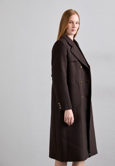 Manteau en laine marron avec un design à double boutonnage, des revers crantés, de grandes poches avant et des boutons dorés. Texture lisse, longueur au genou.