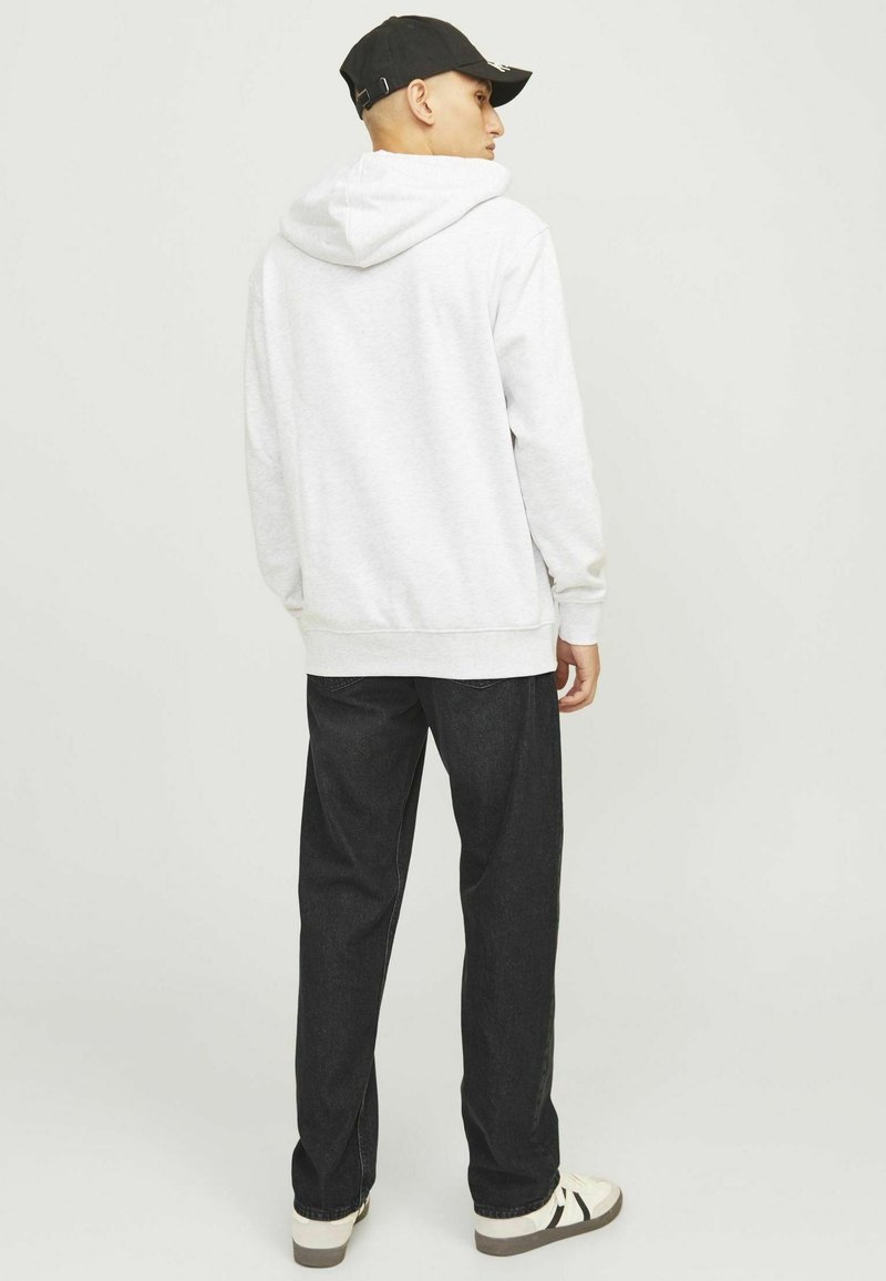 Szara bluza z kapturem na sznurki, z prążkowanymi mankietami, połączona z ciemnoniebieskimi dżinsami i białymi trampkami z czarnymi paskami.