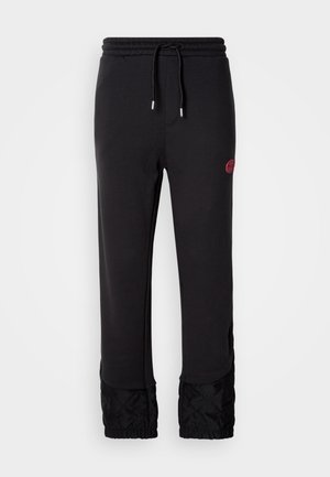 Melni sporta bikses ar aukliņu jostā, kas raksturīgas ar melniem kviltiem akcentiem pie piedurknēm un nelielu bordo logo uz augšstilba.