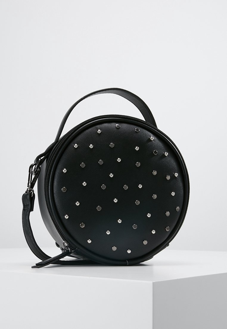 Black circular handbag with a zip closure and a short handle, featuring metallic studs evenly spaced on the front. Smooth leather texture.