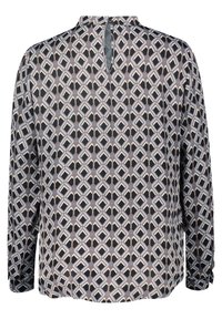 Blouse à manches longues avec motifs géométriques en losange noirs, blancs, gris et beige, et une petite fermeture à bouton au dos du col.